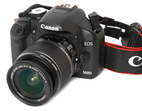 Canon EOS 500D Digital SLR camera with lens and strap.