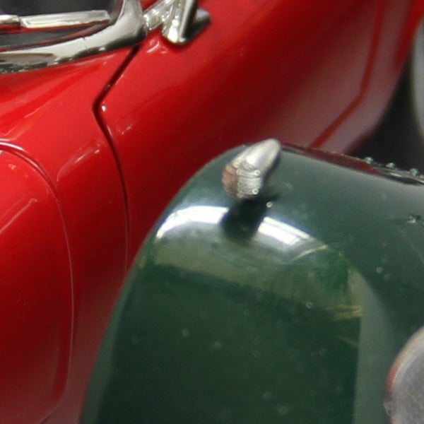 Close-up of a snail on a vintage red car hood.