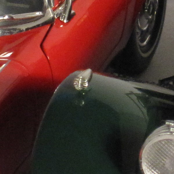 Close-up of a classic car's shiny hood ornament.
