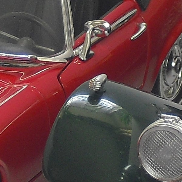 Close-up of a vintage red car's detail with chrome features
