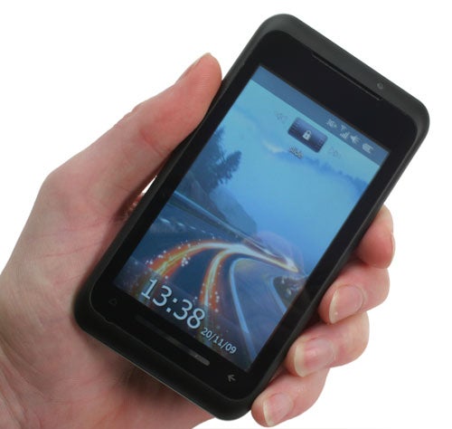 Hand holding Toshiba TG01 smartphone displaying time and date.