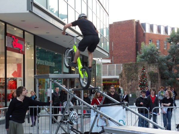 Person performing bike stunt in front of onlookers.