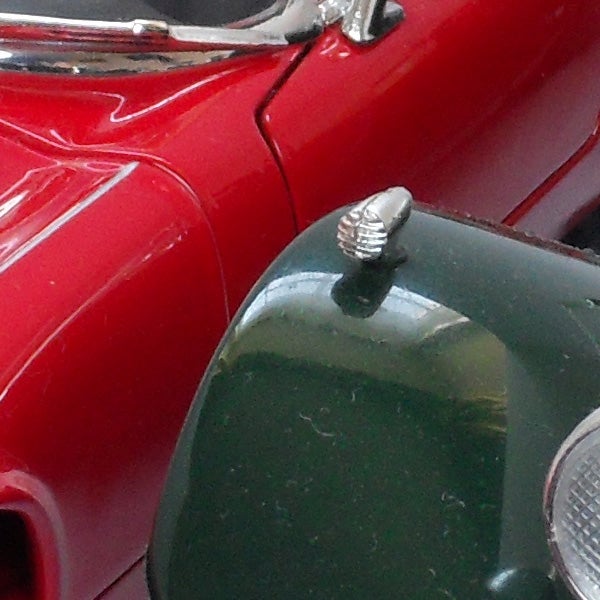 Close-up of a red car's shiny side detail.
