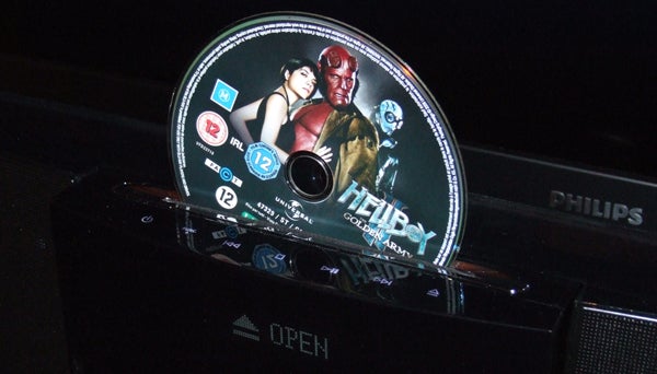 Blu-ray disc protruding from a black soundbar's disc slot