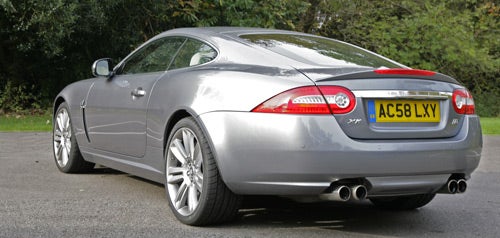 Silver Jaguar XKR Coupe rear view parked on tarmac.
