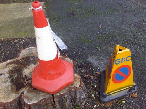 Traffic cone and no parking sign on wet ground.
