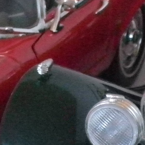 Close-up photo of classic red car hood and headlight