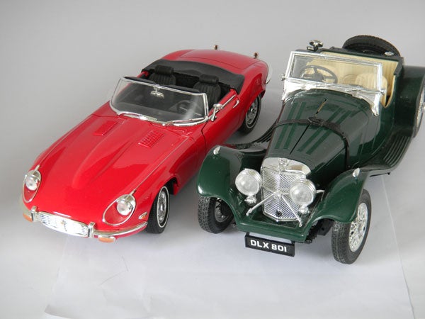 Two model cars, a red sports car and a green classic car.