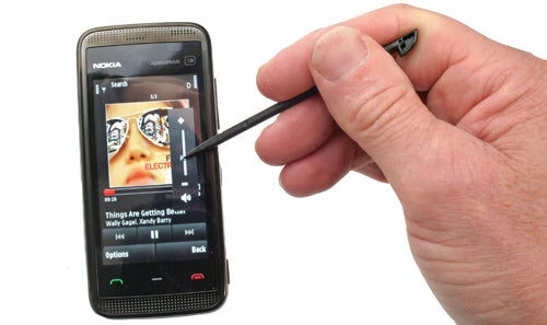Hand holding Nokia 5530 XpressMusic with stylus.