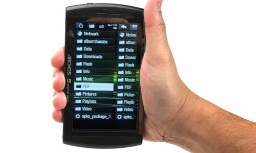 Hand holding Archos 5 Internet Tablet displaying menu.