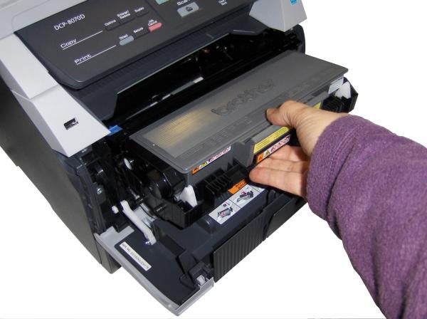 Hand replacing toner in Brother DCP-8070D printer.