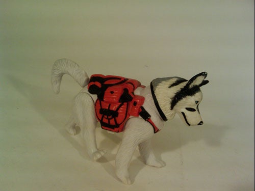 Plastic toy dog with red backpack on white background.