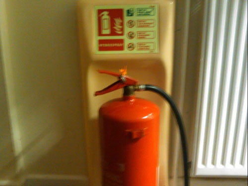 image of a red fire extinguisher against a wall.