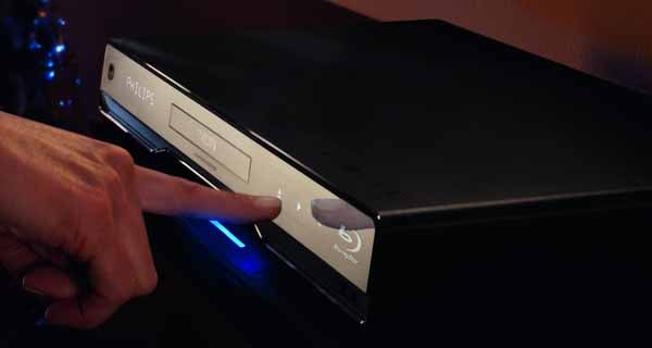 Finger pressing play on a Philips BDP7500 Blu-ray Player.