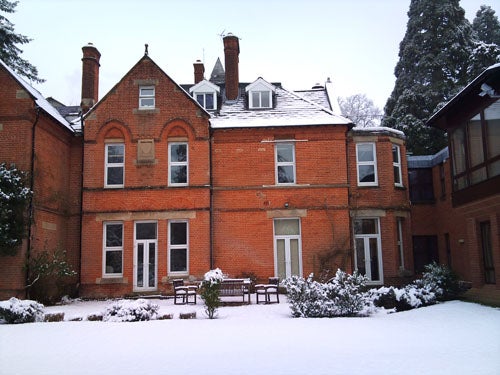 Snow-covered garden in front of a red brick house.