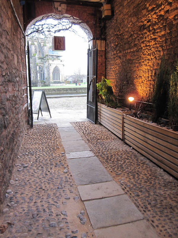 Photo taken with Canon IXUS 120 IS showing a stone archway and cobblestone path.