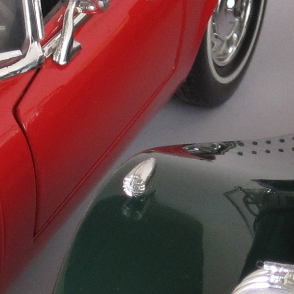 Close-up of a red toy car reflected on a shiny surface