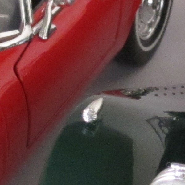 Close-up of a classic red car reflected on a shiny surface.