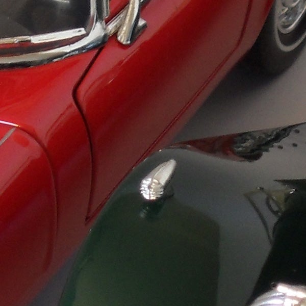 Close-up of classic red car reflecting on shiny surface.