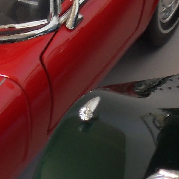Close-up of a red car reflecting on a shiny surface.