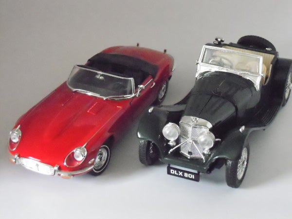 Photograph of two model cars, red and black, side by side.