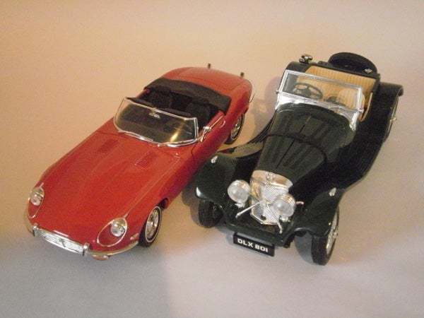 Two vintage model cars displayed on a table.