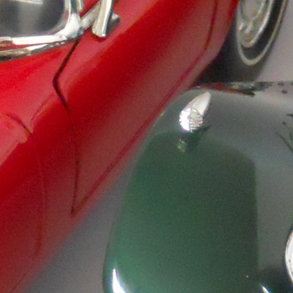 Close-up of red and green vintage cars with chrome details.