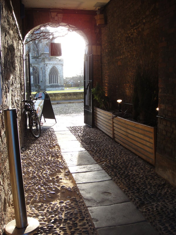 Sunlit cobblestone alley with a view of a church.