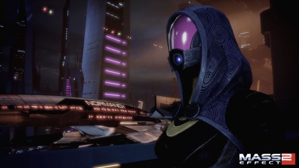 Character in futuristic armor overlooking a cityscape at night in Mass Effect 2.