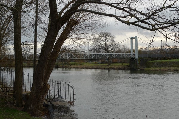 Overcast sky over a river with a bridge and trees