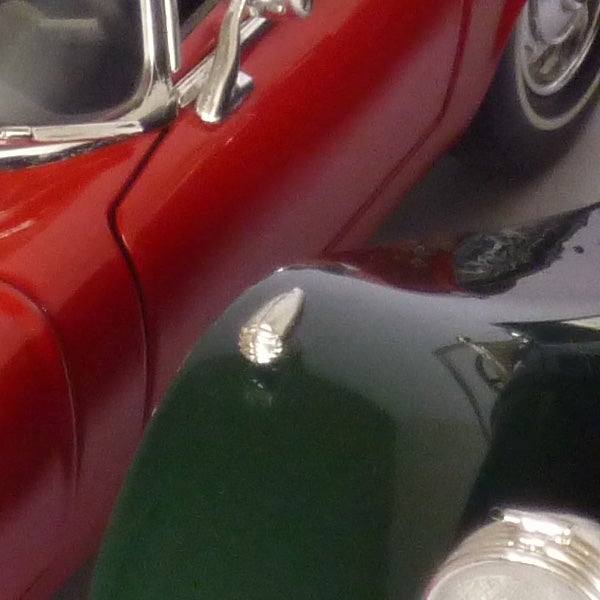 Close-up of vintage red car model captured with Panasonic camera.