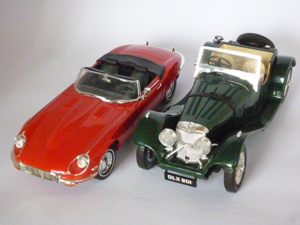Two model cars, red and green, on a grey background