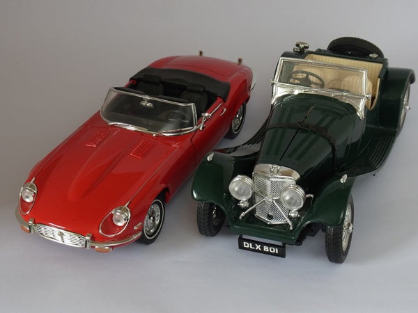 Two model cars, a red Jaguar E-Type and a green classic convertible.