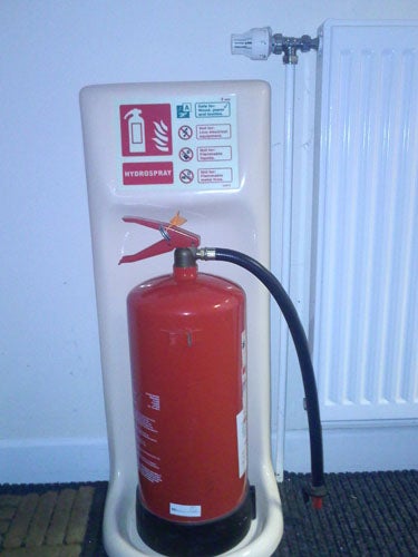 Fire extinguisher standing next to a radiator and instructions sign.