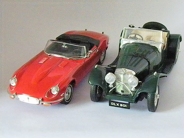 Two vintage model cars displayed on a grey background.