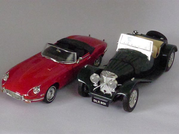 Two vintage model cars on display, one red and one black.