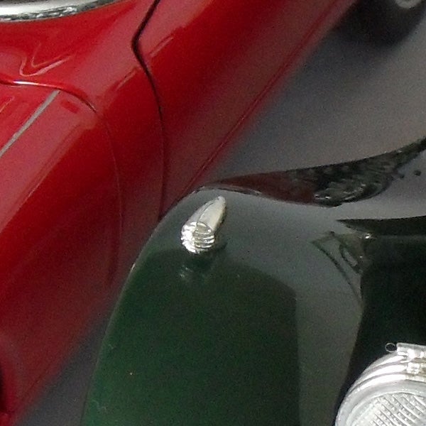 Close-up of car hood and headlight reflections.