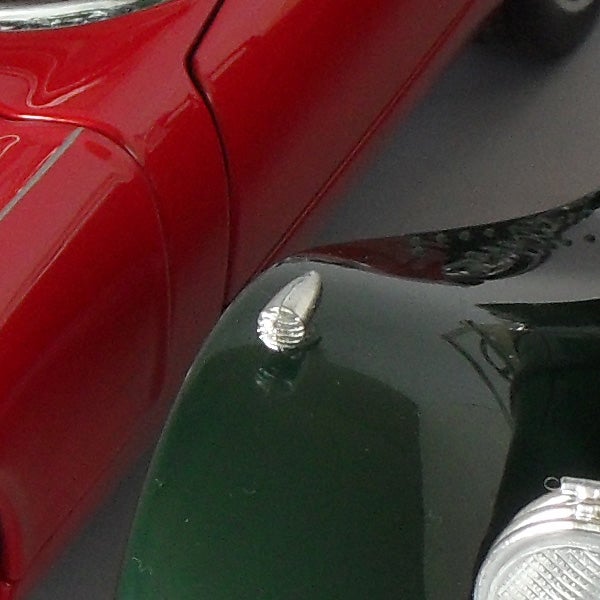 Close-up of a red and green toy car collision.