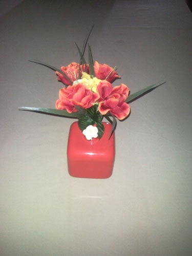 Vase with red and yellow flowers on a table.