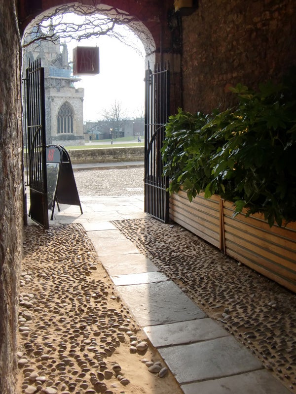 View from stone archway with open gates onto a sunny courtyard