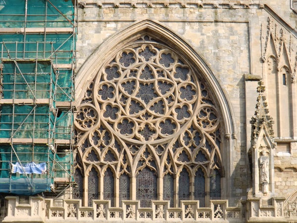 Detailed stonework of a large cathedral window with scaffolding.