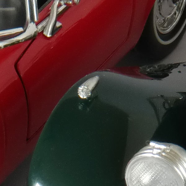 Red vintage car with water droplets on hood.