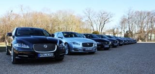Line of Jaguar XJ cars parked outdoors in daylight.