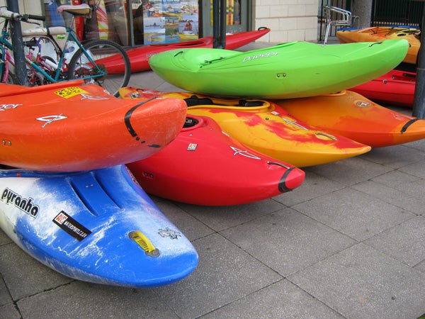 Colorful kayaks stacked on a sidewalk.