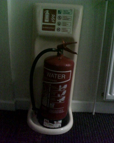 Water fire extinguisher on floor stand near sign