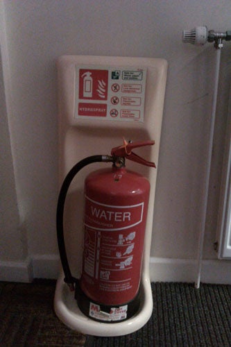 Red water fire extinguisher placed in a stand.