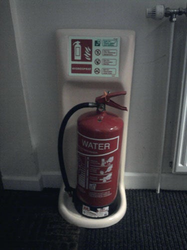 Red fire extinguisher mounted on wall with instructions
