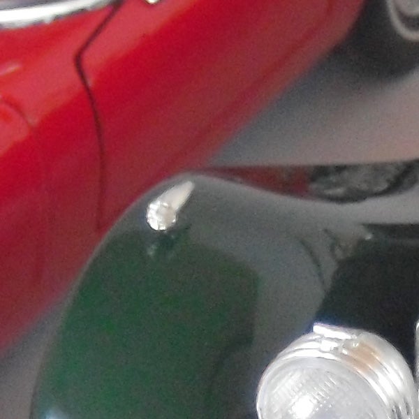 Close-up of a red vehicle's rear light and chrome detail.