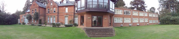 Panoramic photo of a brick house with large windows and lawn