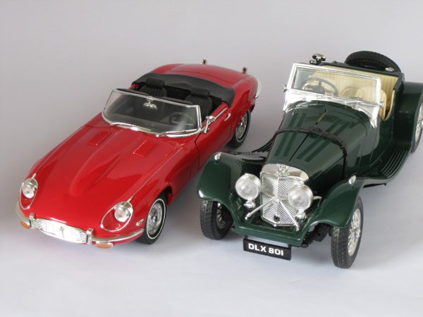 Two model cars, a red sports car and green classic convertible.